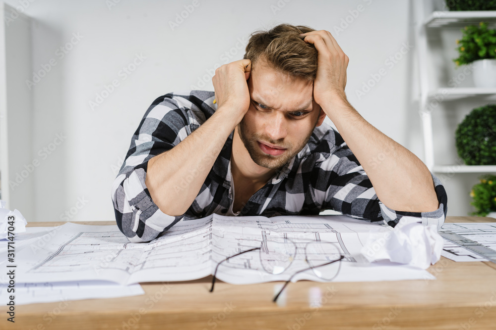 Young adult architect freelancer working in professional bureau with blueprints