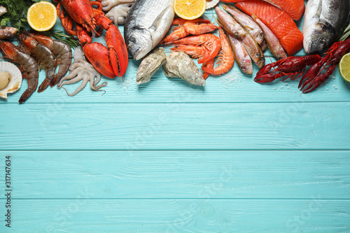 Fresh fish and different seafood on blue wooden table, flat lay. Space for text photo