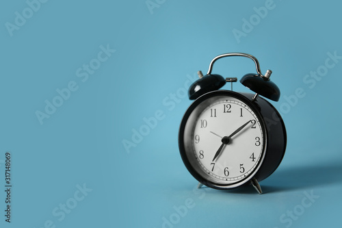 Alarm clock on light blue background, space for text. Morning time
