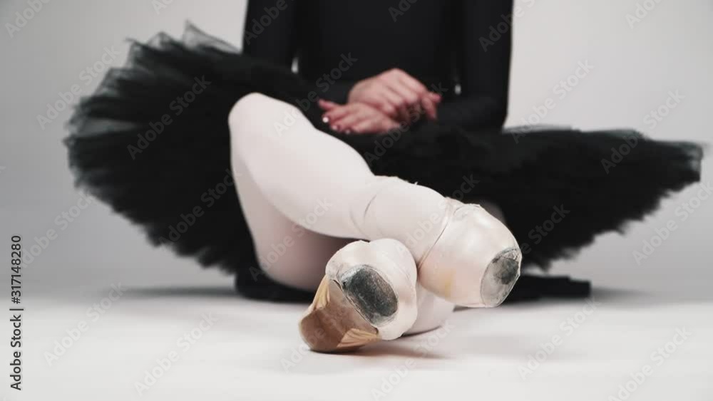 Beautiful young girl ballet Dancer in a black tutu and ballet shoes sitting on white background. Slow motion Beautiful young girl ballet Dancer in a black tutu and ballet shoes sitting on white background. Slow motion