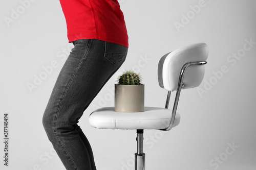 Woman sitting down on chair with cactus against white background, closeup. Hemorrhoids concept