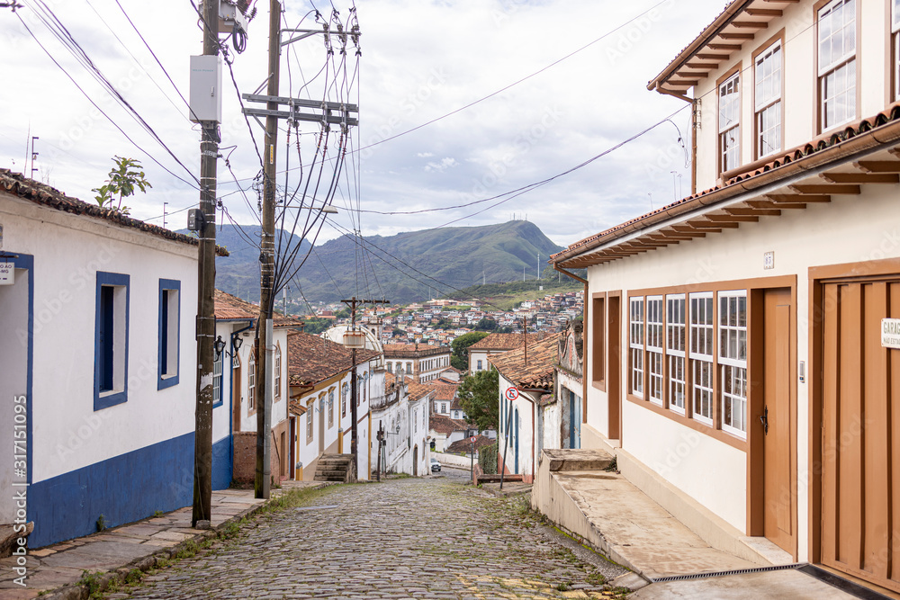 Steep descending cobble street of mining and colonial city in Minas with typical facades on either side