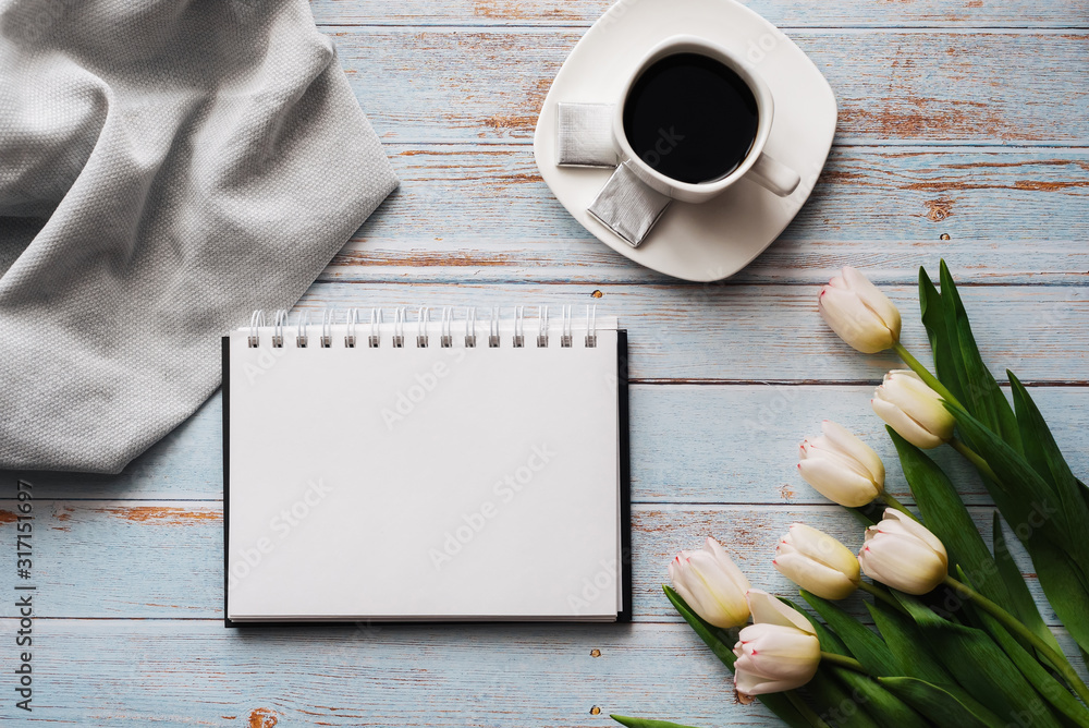 Bouquet of white tulips with an empty notebook, a Cup of coffee on a wooden background