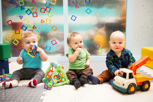 Fotografie, Obraz Three Babies Sitting Up and Playing with Toys