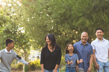Happy Asian family walking and talking outside.