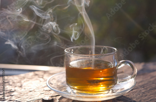 Tea cup with smoke on the wooden table and the morning light