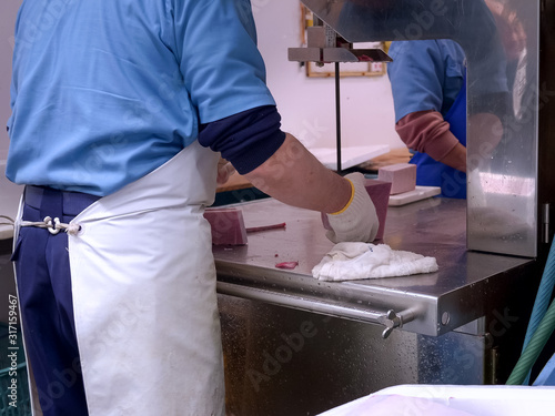 workers cut frozen tuna at tsukiji fish market in japan