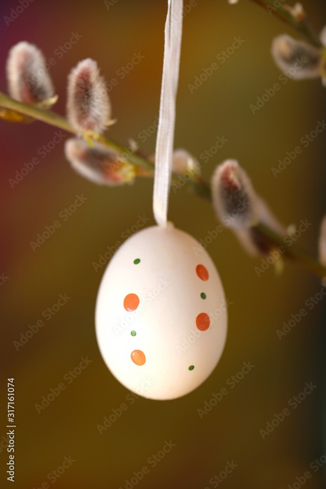Easter time.Decorative easter white speckled egg on a willow branch on a blurry brown background.Spring festive easter background Easter time.Decorative easter white speckled egg on a willow branch on a blurry brown background.Spring festive easter background
