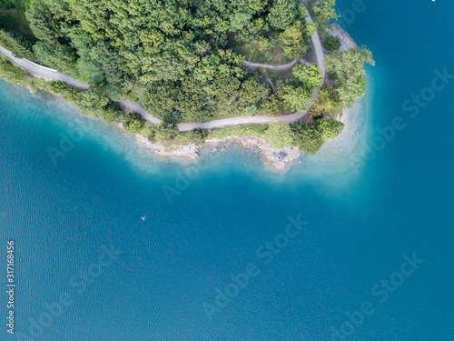 Earth's line. A vertical perspective of the ground's colors and shapes. Drone aerial view of the lake Ledro. A natural alpine lake. Amazing turquoise, green and blue natural colors. Italian Alps