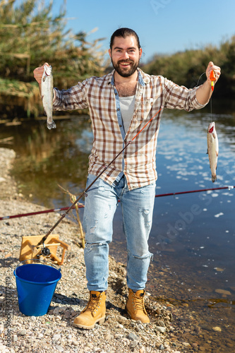 Positive fisherman holding catch freshwater fish in hands