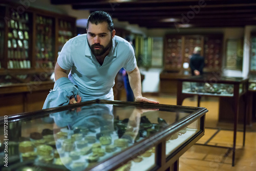 Attentive adult man exploring artworks in glass case in museum