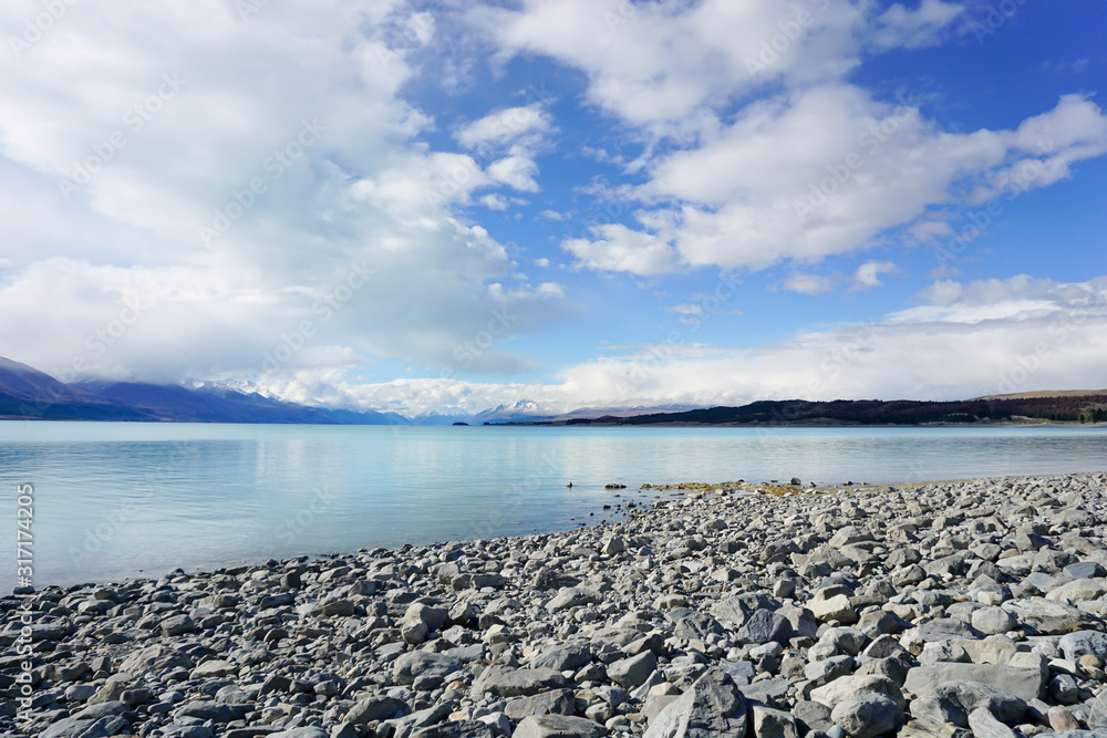The sandy beach by the lake, behind the mountains, there are rocks and the sky. The sandy beach by the lake, behind the mountains, there are rocks and the sky.