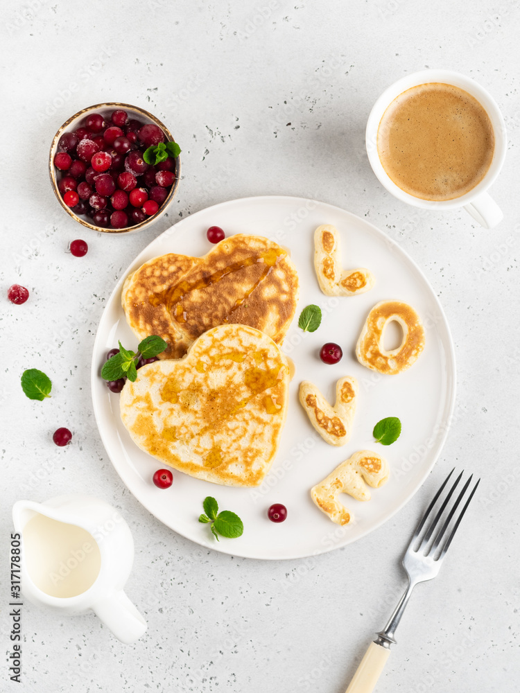 Love pancakes top view. Heart shaped, decorated with mint and frozen cranberries. Morning coffee, tasty beakfast. White background. Love pancakes top view. Heart shaped, decorated with mint and frozen cranberries. Morning coffee, tasty beakfast. White background.