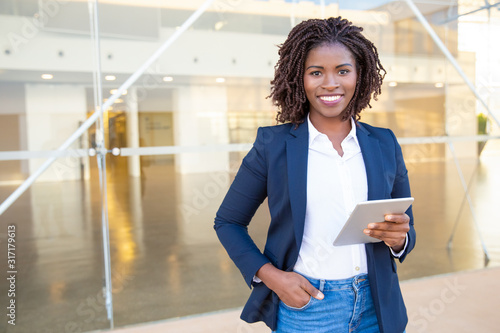 Businesswoman holding tablet pc and smiling at camera. Cheerful young African American businesswoman holding digital tablet and looking at camera. Wireless technology concept photo
