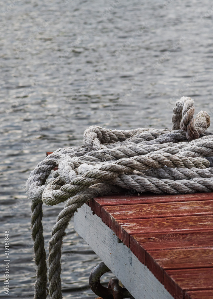 Shabby rope on a wooden pier on a background of water