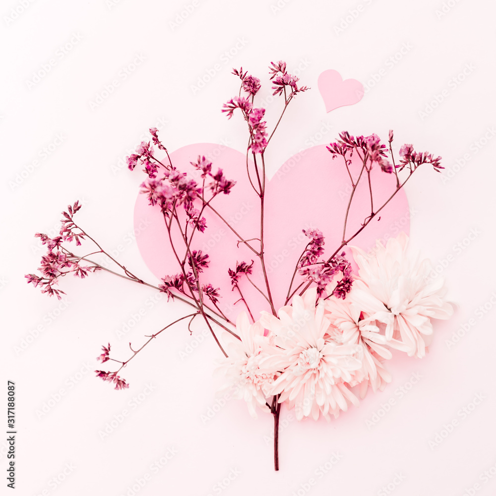 A large pink heart decorated with small pink flowers branch and some chrysanthemum on a pink tint background A large pink heart decorated with small pink flowers branch and some chrysanthemum on a pink tint background