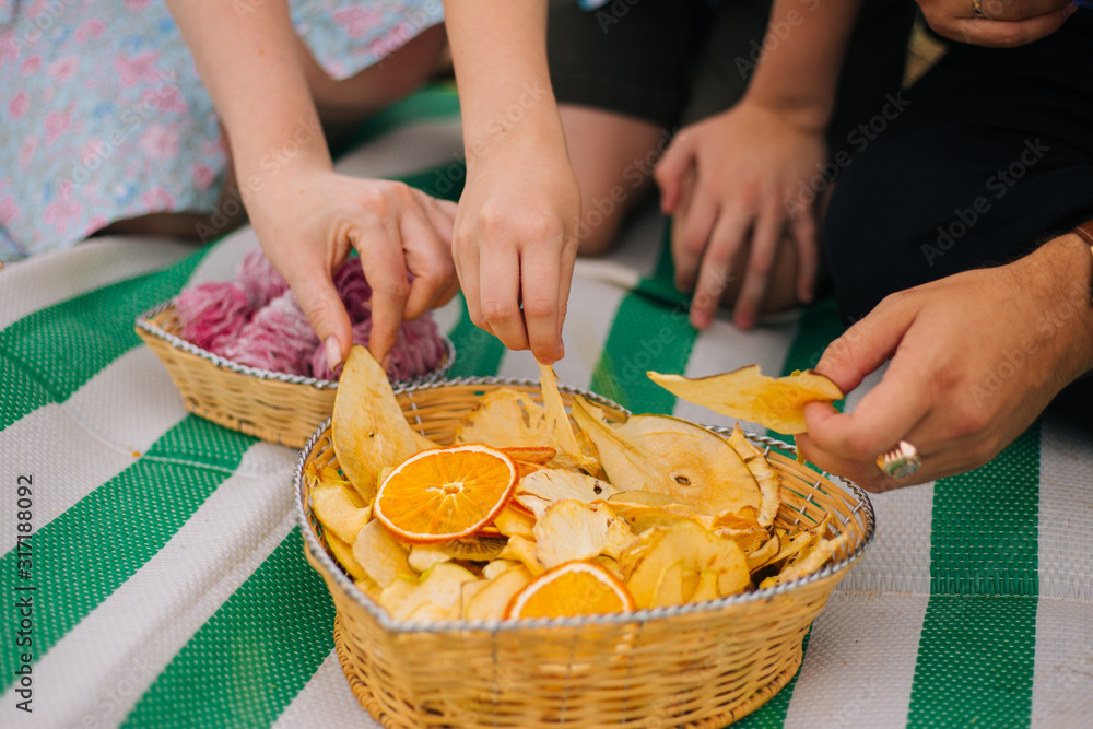 Hands take fruit chips from the basket. Homemade sweets. Family picnic