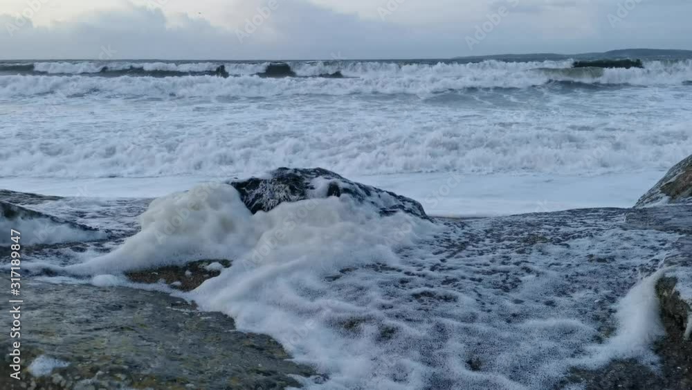 High Spring tides and stormy weather waves with foam on rocks High Spring tides and stormy weather waves with foam on rocks