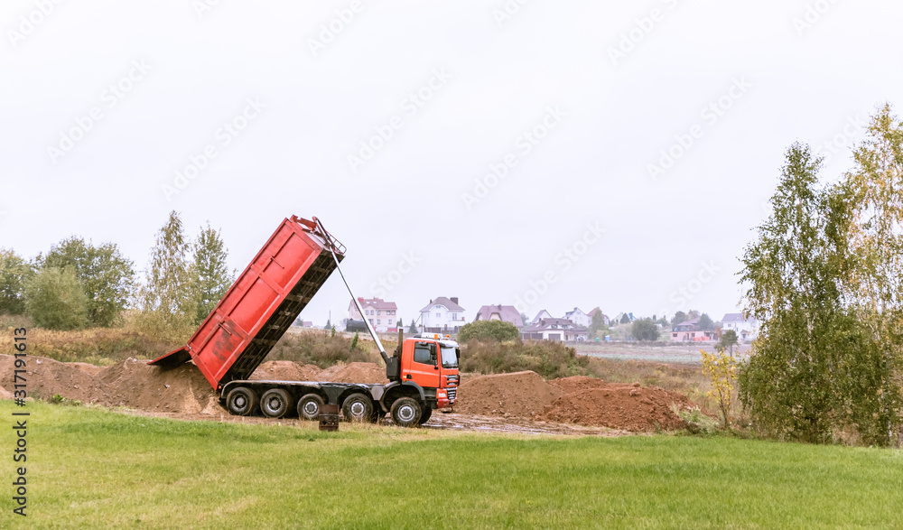 Fototapeta premium A large 70-ton dump truck brought sand to a new construction site to add land