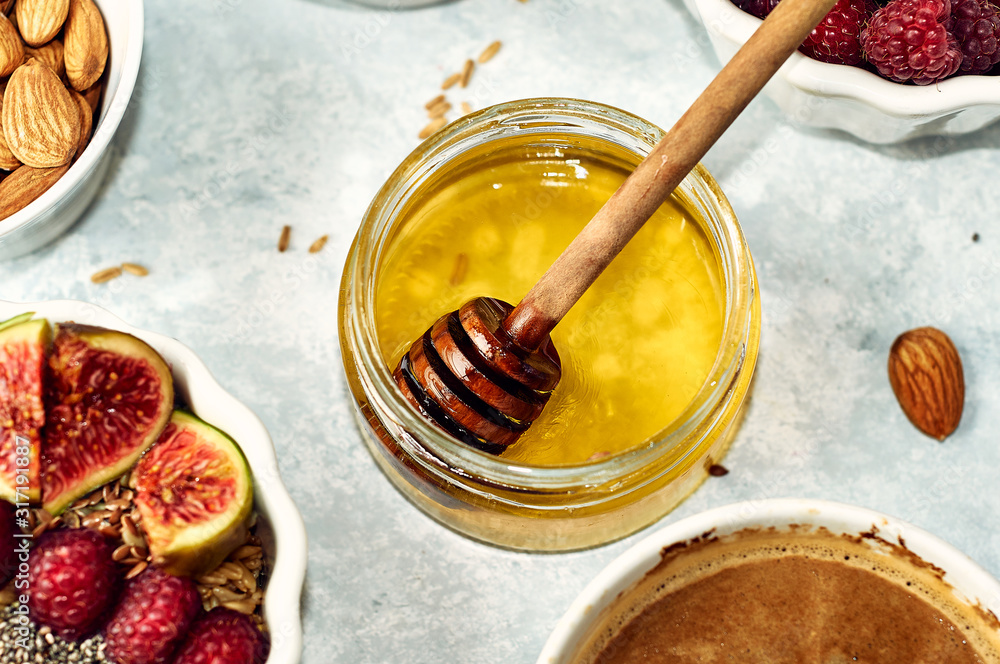Fototapeta premium Honey and honey spoon in a jar on the table