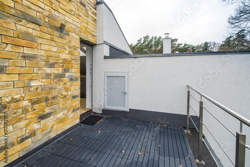 Terrace of a private house with black tile and metallic railings. Second floor. Brick wall.