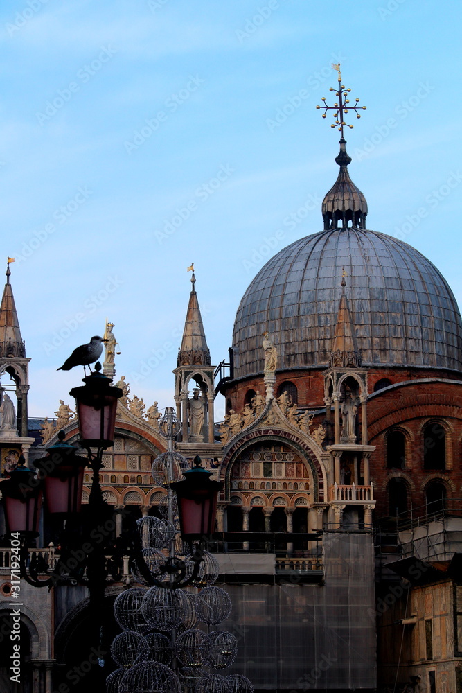 Venice, Italy, December 28, 2018 evocative image of the dome of the Basilica of San Marco on the background  with a seagullperched on a lamppost in the foreground