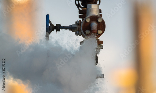 Foto broken valve at the factory hydraulic system, leaking hot liquid and steam under