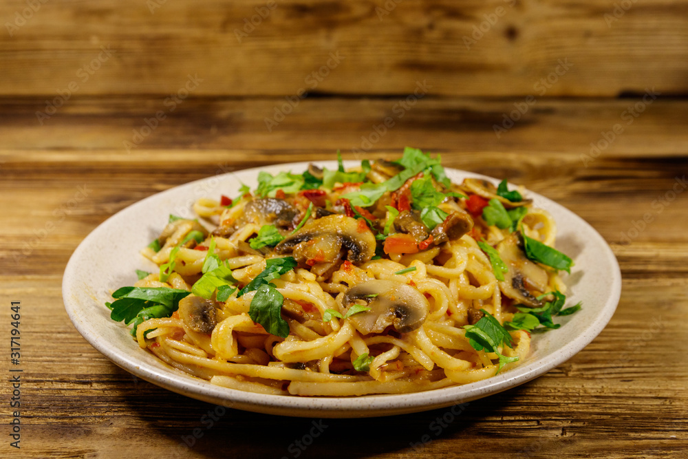 Pasta with mushrooms and tomato sauce on wooden table Pasta with mushrooms and tomato sauce on wooden table