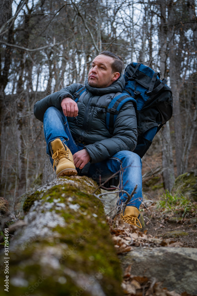 Hiker traveler sits on an old tree in a dense autumn forest Hiker traveler sits on an old tree in a dense autumn forest