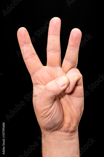 male hand on the black background three fingers raised up