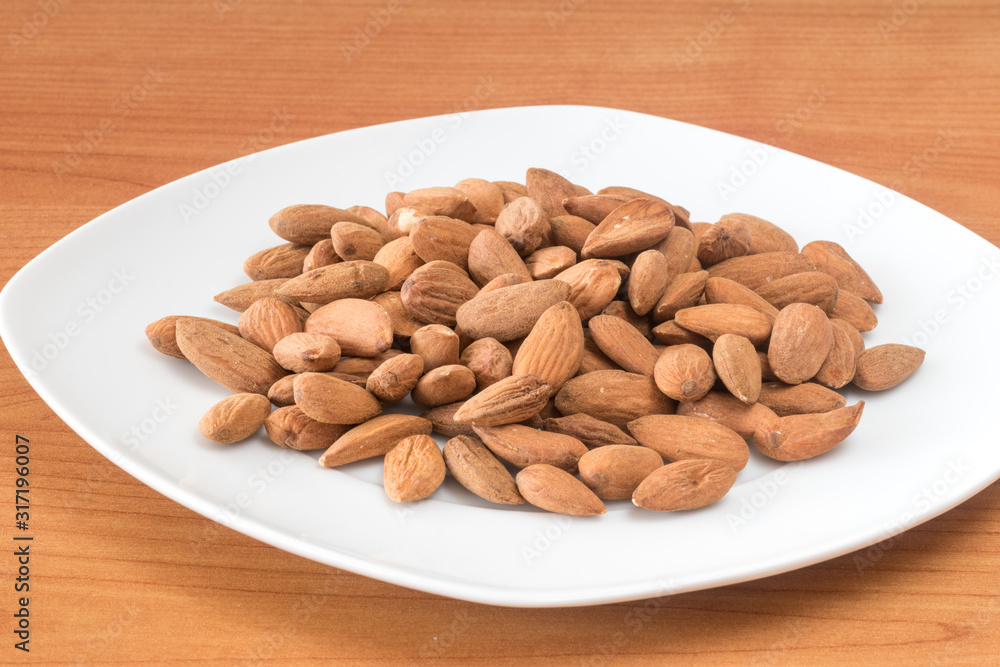 Almonds on white plate on table. Delicious and healthy protein-rich diet food. Almonds on white plate on table. Delicious and healthy protein-rich diet food.