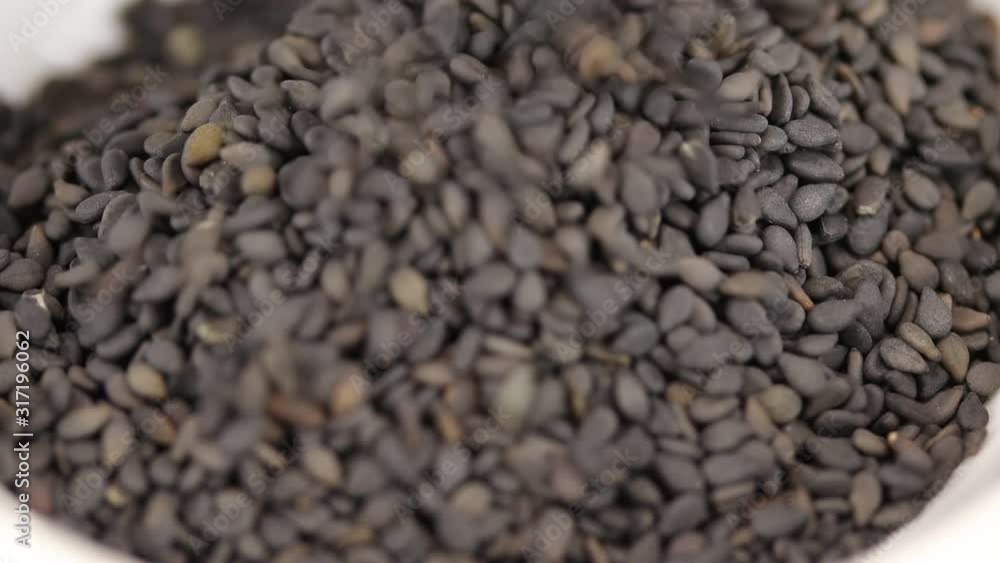 Sesame seeds fall in a glass transparent bowl, close-up Sesame seeds fall in a glass transparent bowl, close-up