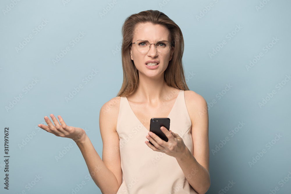 Fototapeta premium Confused woman in glasses hold cellphone having connection problems
