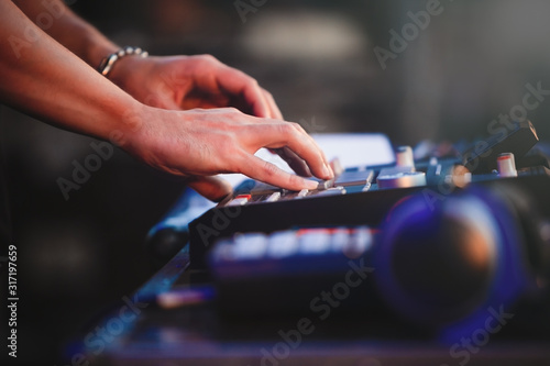 Hands of beatmaker playing new beat on concert stage with professional drum machine device in closeup.Hip hop producer plays electronic music tracks on concert outdoor.EDM musical festival performance photo