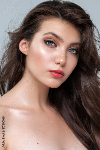Portrait of a very beautiful brunette model with professional day makeup, perfect skin and rich wavy natural hair.