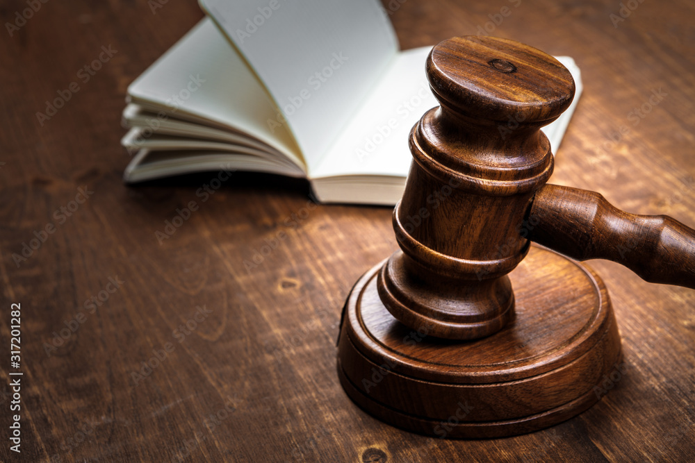 Brown wooden judge mallet on the background of open book Brown wooden judge mallet on the background of open book