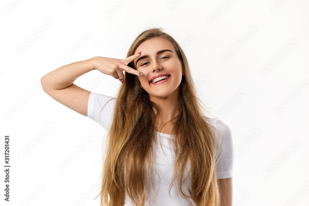 smiling young woman showing victory sign and looking at camera on white background. smiling young woman showing victory sign and looking at camera on white background.