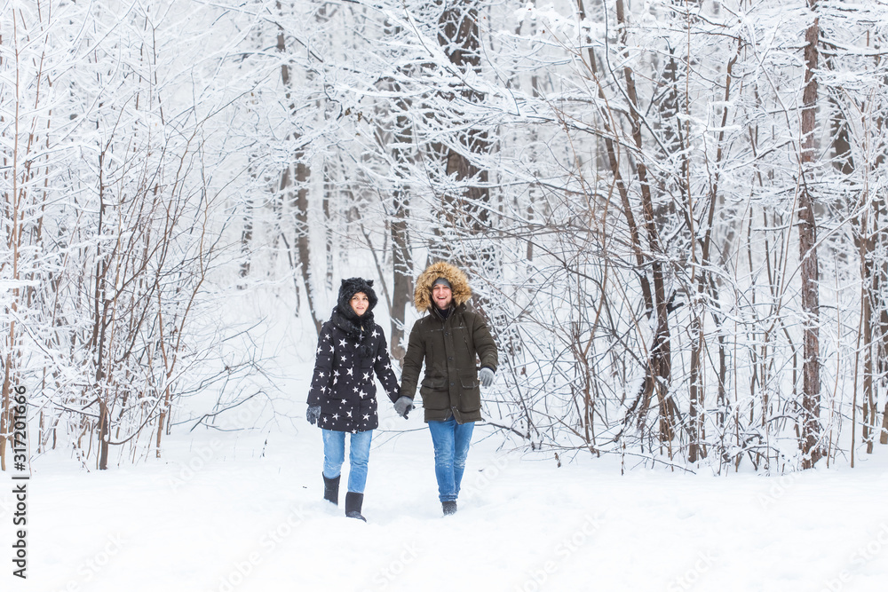 Young couple in love walks in the snowy forest. Active winter holidays.