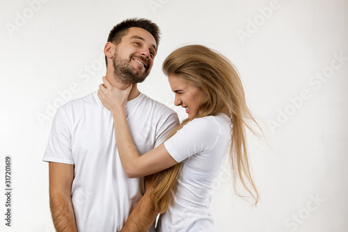 woman jokingly strangles man. angry woman shouting at her happy boyfriend on white background.