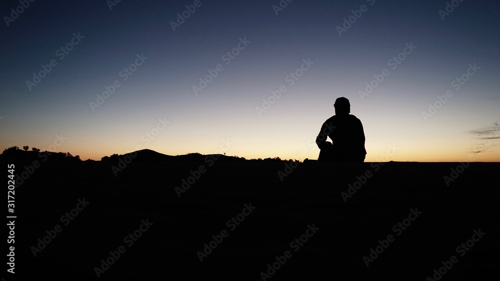 Mann genießt Sonnenuntergang in der Wüste