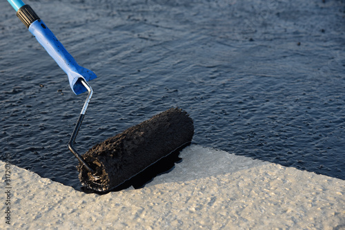 Φωτογραφία Worker applies bitumen mastic on the foundation