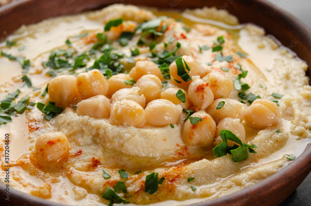Closeup view at Hummus topped with beans olive oil and green coriander leaves on kitchen table Closeup view at Hummus topped with beans olive oil and green coriander leaves on kitchen table