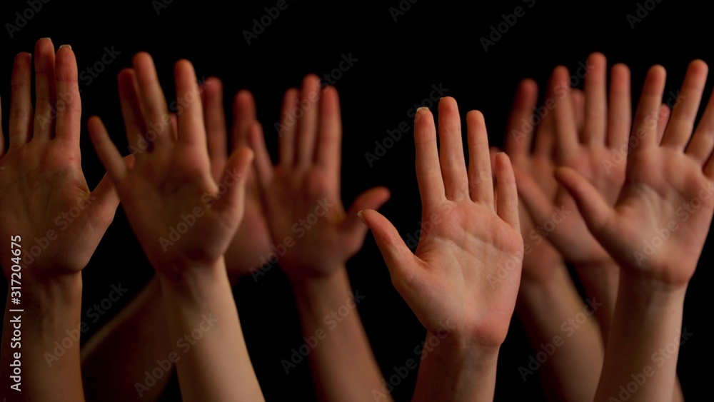 Young people's hands raised up on a black background