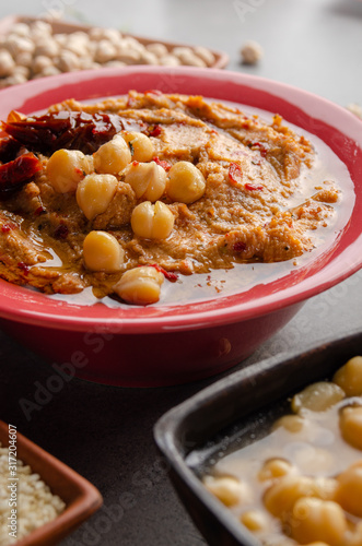 Hummus topped with beans, sun dried tomatoes and olive oil on kitchen table