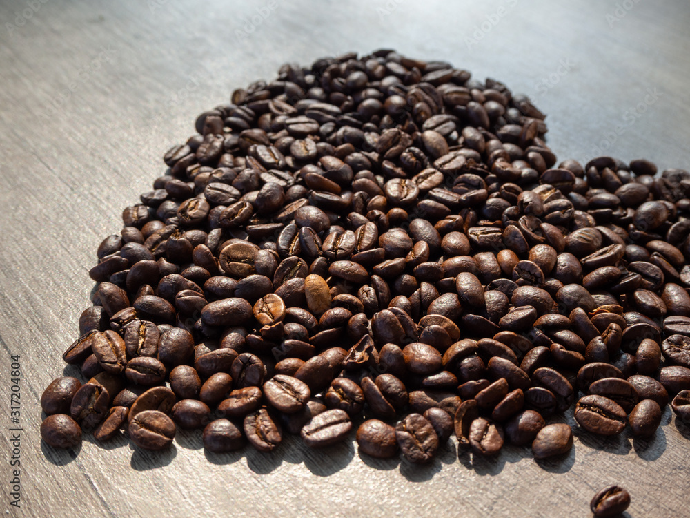Fototapeta premium Valentines Day card - black coffee heart-shaped beans on the surface of a wooden table.