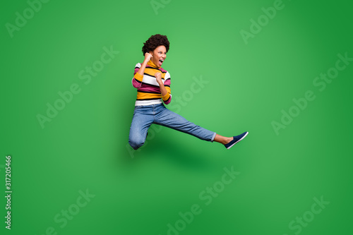 Full length photo of funny crazy afro american girl jump practice autumn sportive kickboxing kick legs fists fight enemy copyspace wear shine beautiful outfit isolated green color background