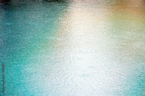 Blue water. Rain. Drops. Surface texture. Pool. Summer. Rainy day.