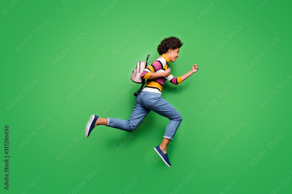 Full body profile side photo of crazy funky afro american girl jump run fast want travel fall journey wear bright shine backpack outfit isolated over green color background Full body profile side photo of crazy funky afro american girl jump run fast want travel fall journey wear bright shine backpack outfit isolated over green color background