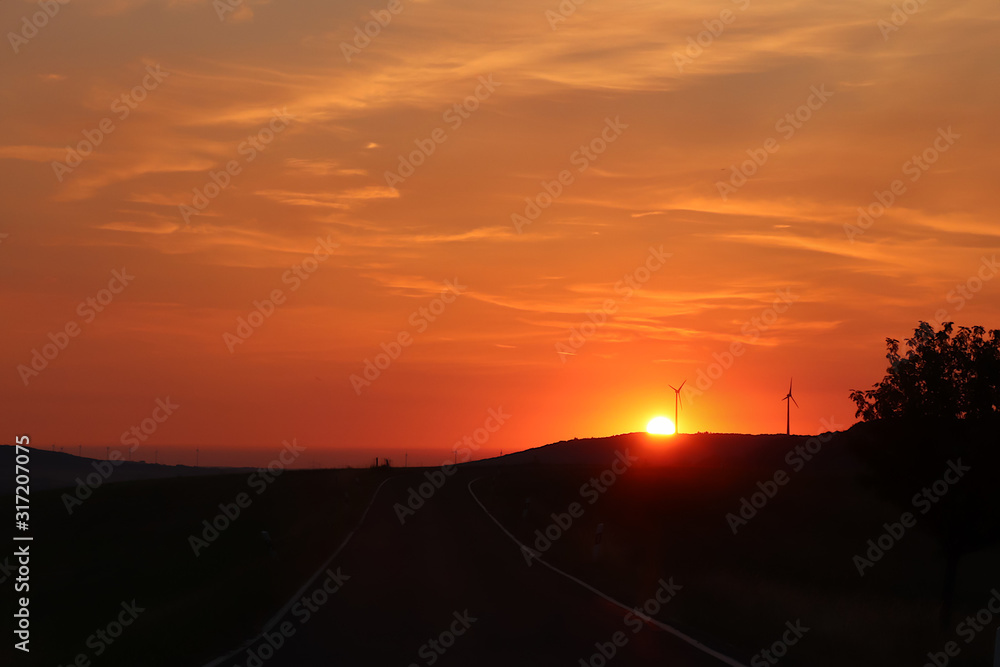 Wind turbines with a bright orange sunrise