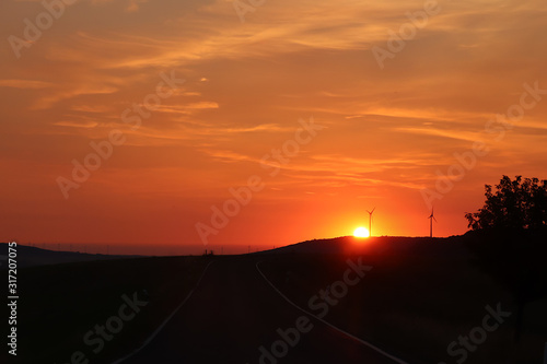 Wind turbines with a bright orange sunrise